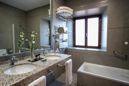 卡塞雷斯阿雷纳莱斯宫殿霍斯皮斯及spa酒店的浴室设有2个水槽、浴缸和镜子