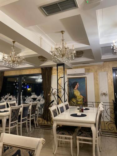 兹拉蒂博尔Zlatibor Hills Apartments Wellness & Spa的用餐室配有白色桌椅和吊灯。