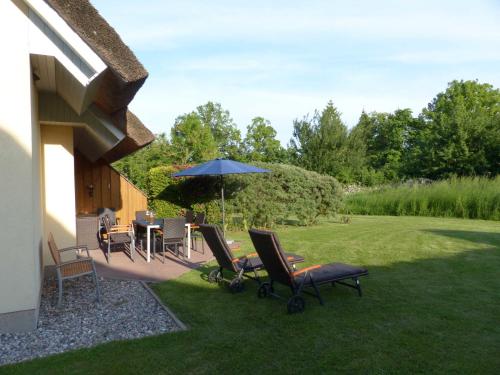 布德明Behagliches Reetdachhaus Eibe 1的庭院配有桌椅和遮阳伞。