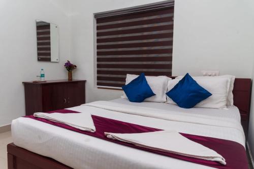 维特利pookode villa的一间卧室配有一张带蓝白色枕头的大床