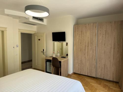 克鲁亚Mervin Hotel的一间卧室配有一张床、一张书桌和一台电视。