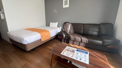 鹿儿岛Apartment Hotel Ecott的配有床和真皮沙发的房间