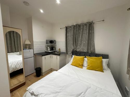 布罗姆利2nd Studio Flat With Great Views in Keedonwood Road With Private Kitchenette and shared bathroom的卧室配有一张带黄色枕头的大型白色床。