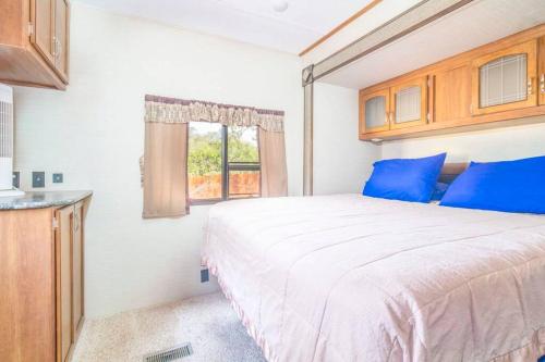摩押Moab RV Resort Outdoor Glamping Destination RV OK40的一间卧室配有一张带蓝色枕头的床和一扇窗户。