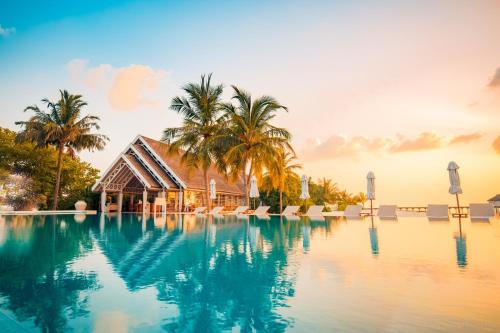 马米基里LUX* South Ari Atoll Resort & Villas的一座带别墅和棕榈树的度假游泳池