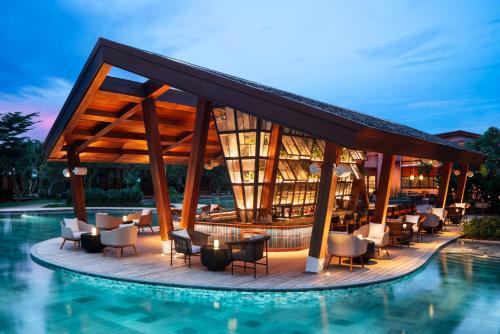 会安New World Hoiana Beach Resort的一个带游泳池和桌椅的度假酒店