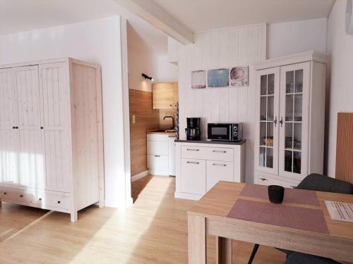 OesterdeichstrichRuhiges 1-Zimmer-Appartement, Büsum (4km), Nordsee的一间厨房,内设白色橱柜和一张桌子
