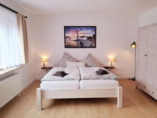 OesterdeichstrichRuhiges 1-Zimmer-Appartement, Büsum (4km), Nordsee的白色的房间里一张白色的床,配有两盏灯
