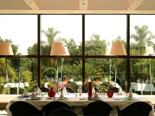 阿尔及尔Sofitel Algiers Hamma Garden的一间带桌子和大窗户的用餐室