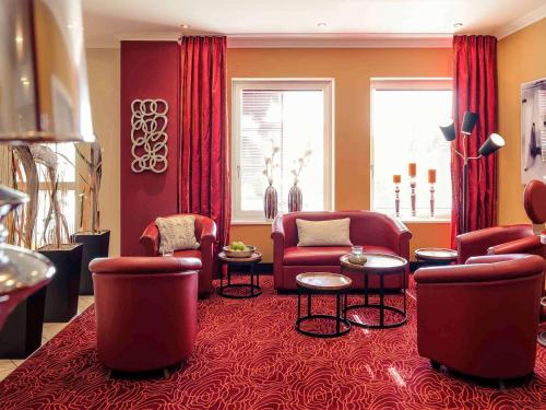 因戈尔施塔特美居因戈尔施塔特酒店的客厅配有红色的椅子和桌子