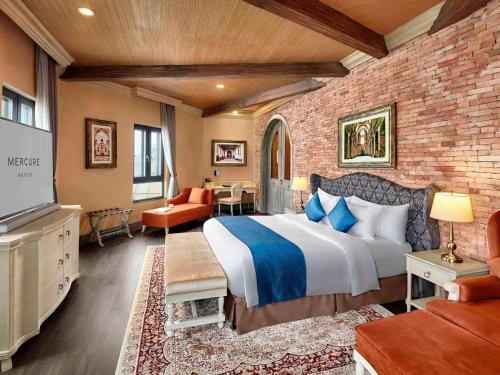 岘港岘港法国村巴纳山美居酒店的一间卧室设有一张大床和砖墙