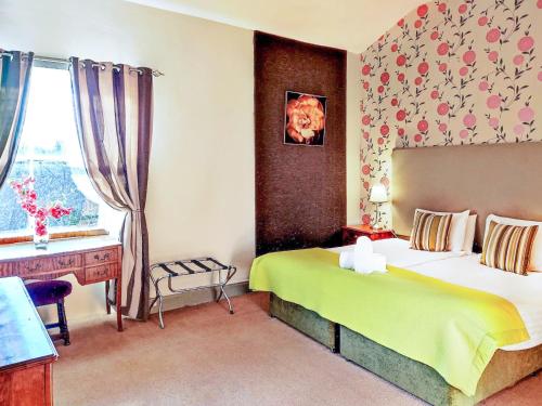 ArnistonThe Mansion House At Kirkhill的一间卧室配有一张床、一张书桌和一个窗户。