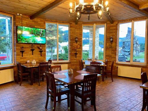 亚列姆切Готель Довбуш的餐厅设有木桌、椅子和窗户。