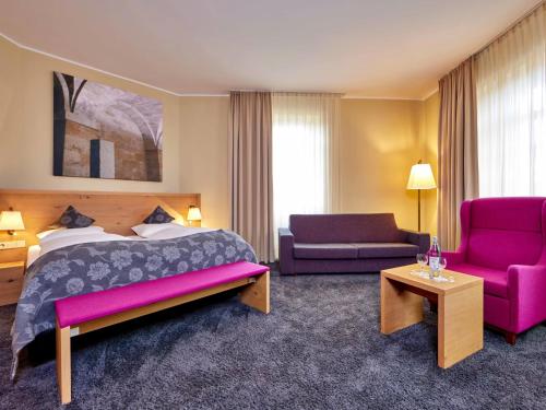 希莱斯海姆Augustiner Hotel的酒店客房配有一张床、一张沙发和椅子。