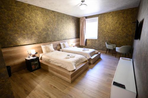 InđijaMonogramlux的一间卧室配有两张床和一张桌子及椅子