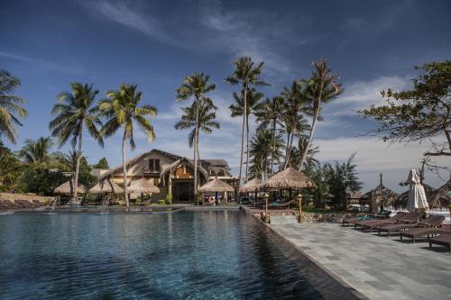 美奈阿罗马海滩Spa度假酒店的一个带椅子和棕榈树的度假游泳池