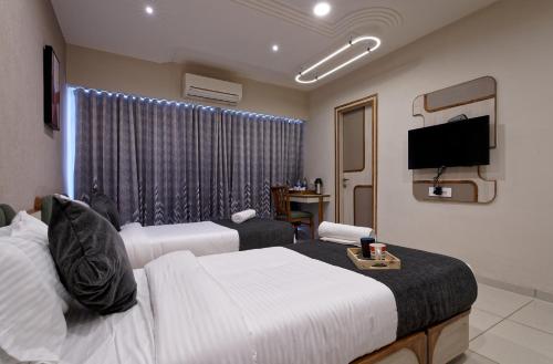 艾哈迈达巴德Exora Inn的酒店客房设有两张床和一台平面电视。