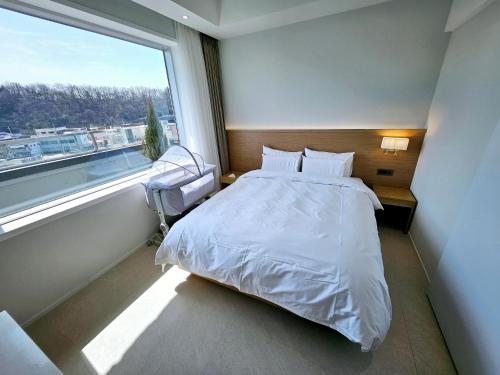群山市Gran Hotel的一间卧室设有一张床和一个大窗户