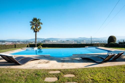 吉马良斯Casa Tranquilidade - Casa moderna com piscina的一个带两把躺椅和棕榈树的游泳池
