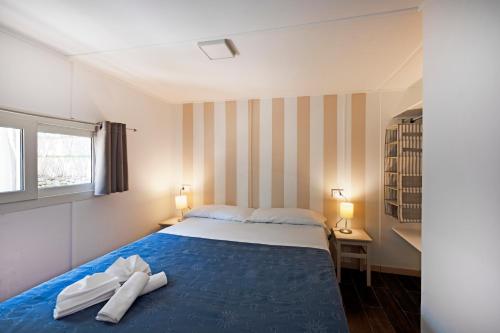 纳拉诺Camping Villaggio Nettuno的一间卧室配有一张带两条白色毛巾的床