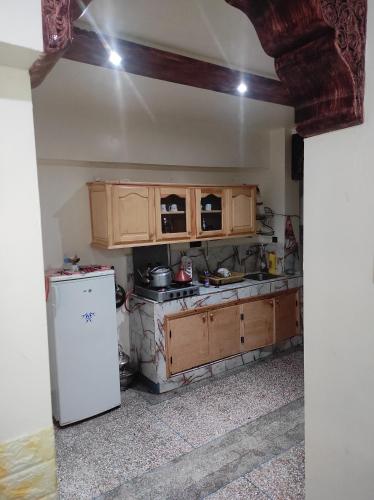马拉喀什Appartement situé à 5 minutes à pied de l'Aeroport de Marrakech的厨房配有木制橱柜和白色冰箱。