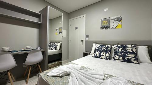 库里提巴09- Studio lindamente decorado! Ideal para casal!!!的一间卧室配有一张床、一张书桌和一面镜子
