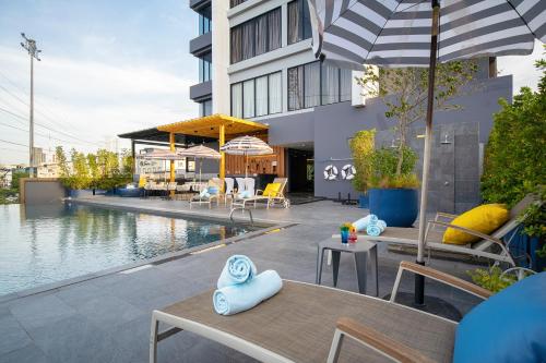 曼谷Thaya Hotel Bangkok的一座带桌椅的游泳池位于大楼旁