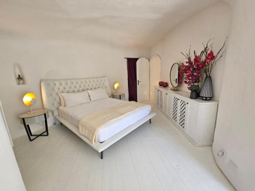 蓬扎Maridea - La Caletta - Luxury Villa的一间白色的卧室,卧室里摆放着床和鲜花
