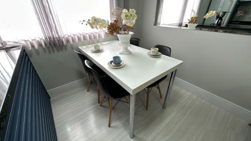 库里提巴08- Studio perfeito para família! Aconchegante e novo!的一张带椅子和杯子的白色桌子,上面有花瓶