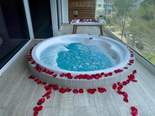 卡塔赫纳Dominique Cartagena, Beautiful 2 Bedroom Apartment的阳台上的热浴盆四周环绕着红玫瑰