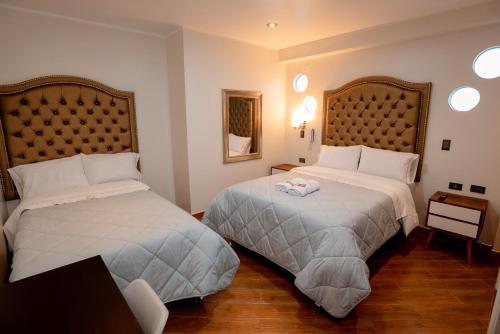 阿亚库乔Hotel Melthon Urbans的酒店客房设有两张床和一张桌子。