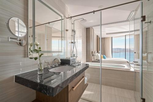 芽庄Oceanfront Panorama Nha Trang的浴室配有盥洗盆、镜子和浴缸