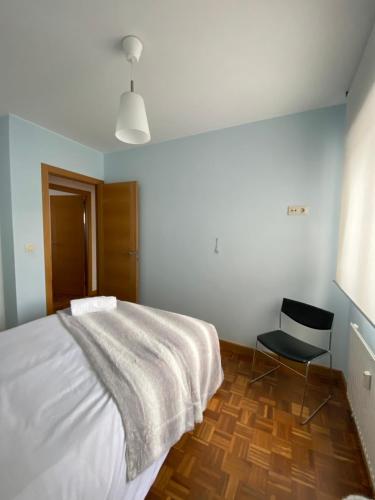 拉科鲁尼亚Apartamento en A Coruña - Cuatro Caminos centro ciudad的卧室配有白色的床和黑椅