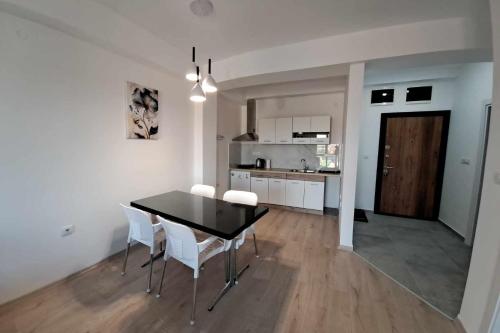 斯科普里Apartment B&S的厨房以及带黑桌和白色椅子的用餐室。
