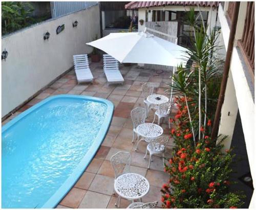 塞古罗港Pousada Porto Jandaias的一个带游泳池、椅子和遮阳伞的庭院
