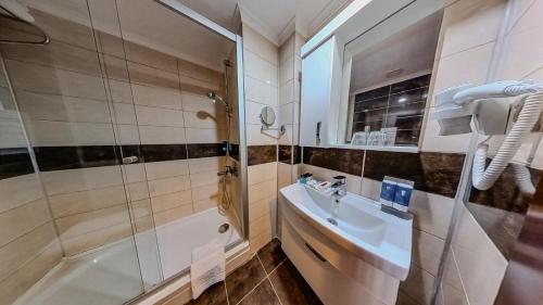 锡德Adella Side Hotel的带淋浴、盥洗盆和浴缸的浴室