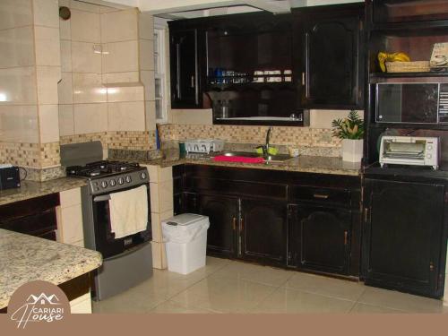 埃雷迪亚Full house, 11BR, 12BA, 10 min from SJO Airport的厨房配有黑色橱柜和炉灶。
