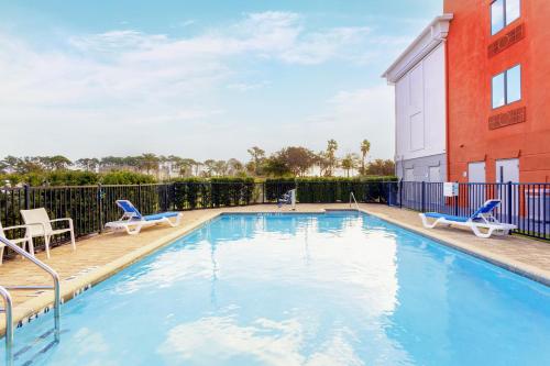 杰克逊维尔Holiday Inn Express Hotel & Suites Jacksonville - Mayport / Beach, an IHG Hotel的一座带椅子的游泳池以及一座建筑
