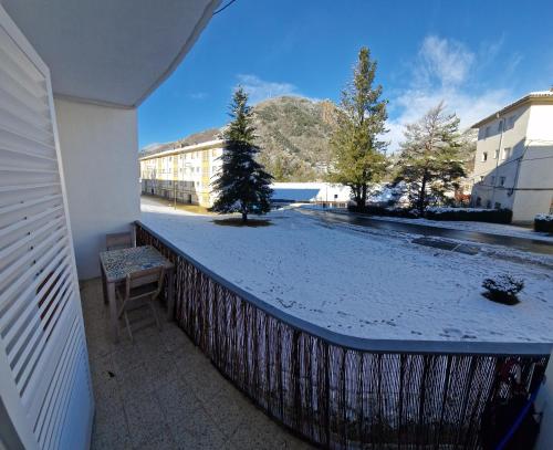里贝斯的弗里瑟Apartamento CREMALLERA Ribes de Freser的阳台的雪覆盖庭院上有一棵树