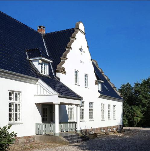 普赖斯特Jungshovedgaard Bed & Breakfast的黑色屋顶的白色房子