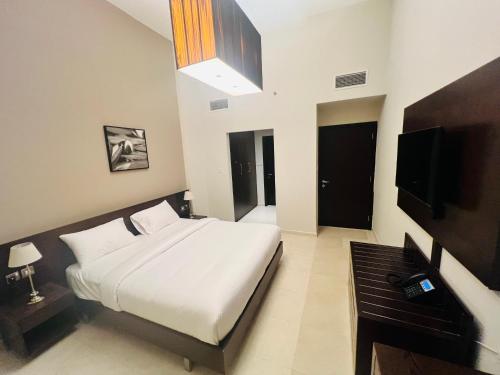 迪拜AlRaef Luxury Apartments的卧室配有白色的床和电视。