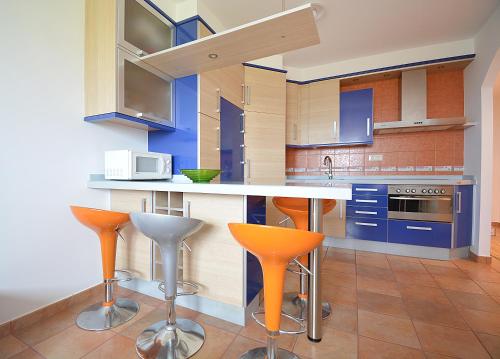 里贝拉Apartamento con jardín en Playa de Corrubedo的厨房配有蓝色橱柜和橙色酒吧凳