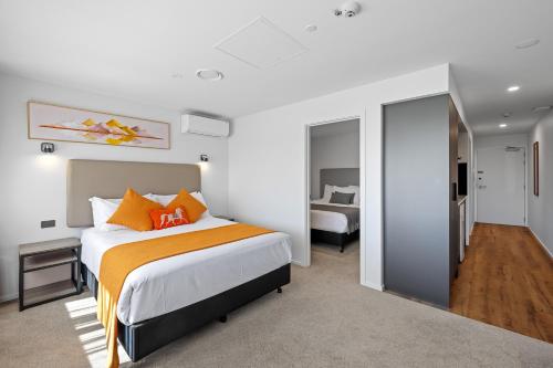 基督城Golden Hotel的一间卧室配有一张带橙色枕头的大床
