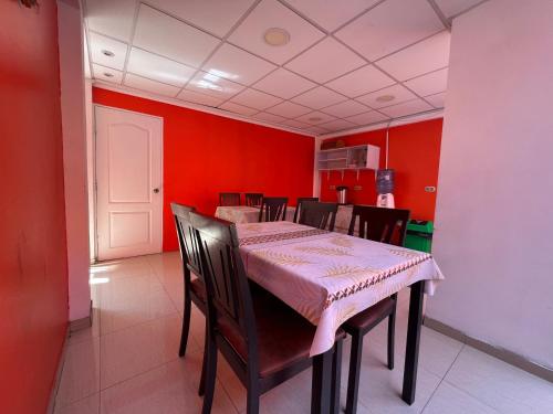 伊基克Hotel Casa del profesor Iquique的一间拥有红色墙壁和桌椅的用餐室