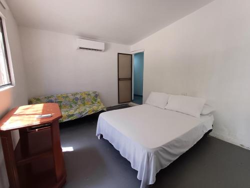 Playa Punta ArenaPunta Arena Beach Hostel的一间卧室配有一张床、一张桌子和一张沙发