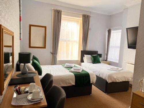 滨海韦斯顿The Grove的酒店客房设有两张床和一张桌子。