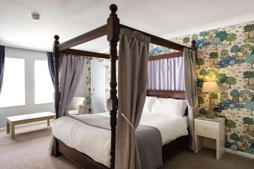 萨顿科尔菲尔德Moor Hall Hotel, BW Premier Collection的一间卧室配有四柱床和花卉壁纸