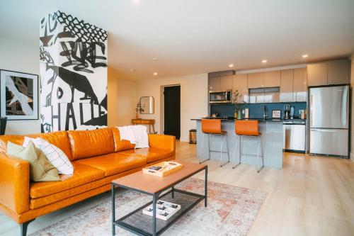 哈利法克斯NEW Stylish 2BR Condo with Views in North End的一间带橙色沙发的客厅和一间厨房