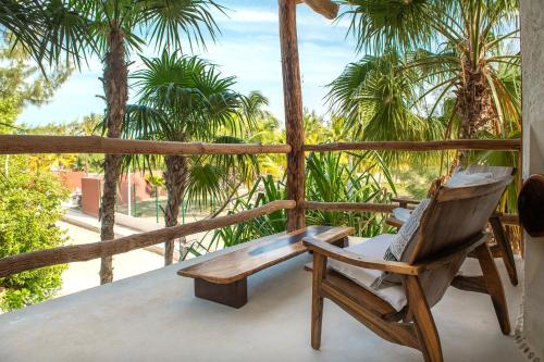 奥尔沃克斯岛Hotel Mawimbi的棕榈树门廊上的木椅