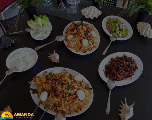 帕西库达Amanda Beach Resort的餐桌上放有食物和勺子的盘子